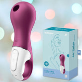 A purple and white personal massager rests next to its sophisticated packaging, adorned with a line drawing of a woman's face. The packaging showcases the names "Satisfyer Lucky Libra" and "Air Pulse Clit Stimulator" against a soft pastel bokeh background, underscoring its promise of clitoral stimulation.
